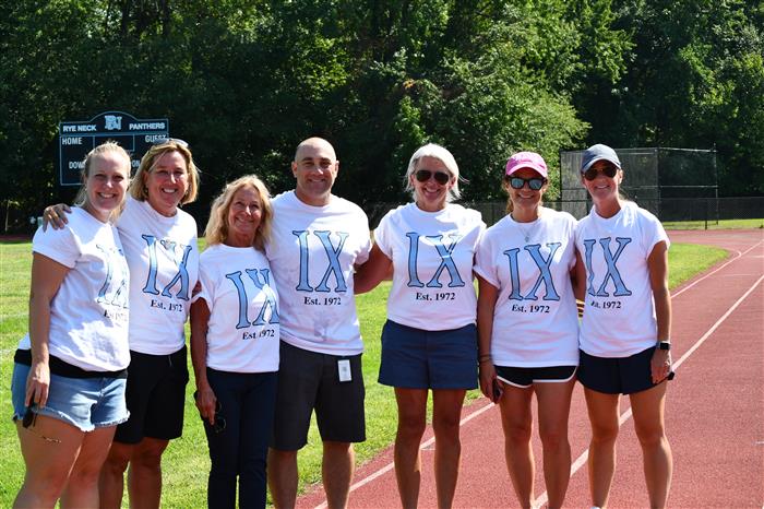 Rye Neck's Title IX committee standing on the track with honored guest