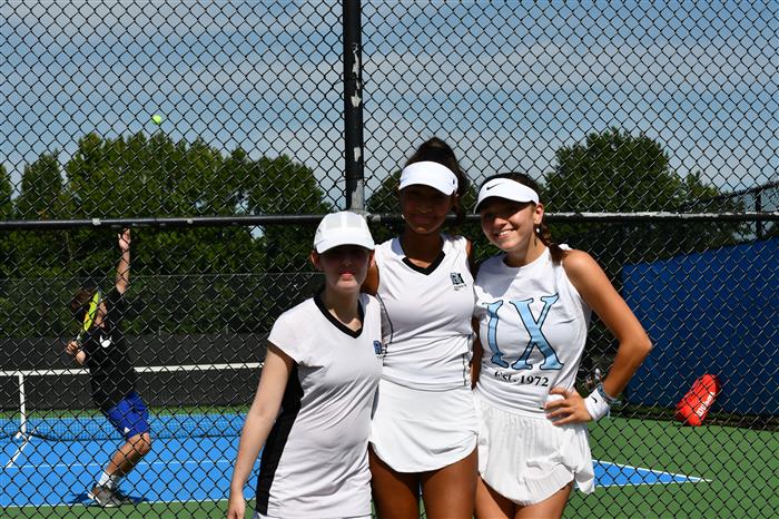3 female tennis players in front of the court
