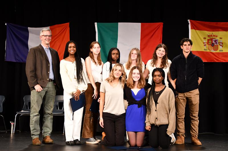 Students inducted for French stand in a group on the stage