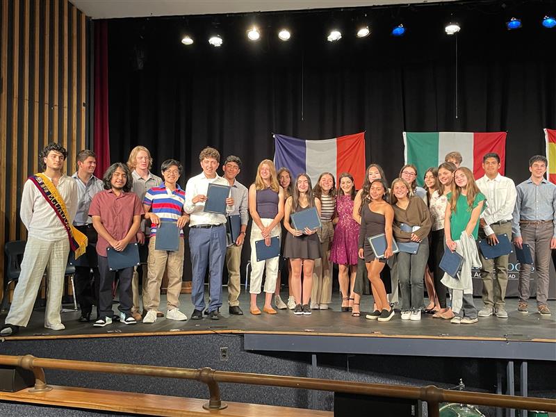 Students inducted for Spanish stand in a group on the stage